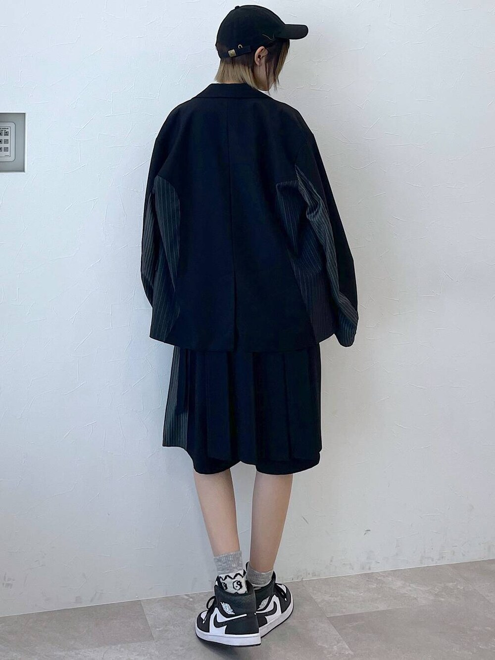 ブラック系のテーラードジャケット、ブラック系のスラックス、ブラック系のキャップを着用したレディースの冬コーディネートの5枚目の写真