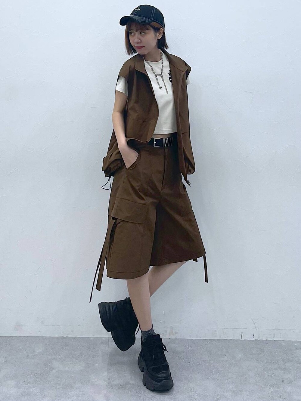 ブラック系のスニーカー、ベージュ系のTシャツ/カットソー、ブラウン系のベストを着用したレディースの夏コーディネートの2枚目の写真