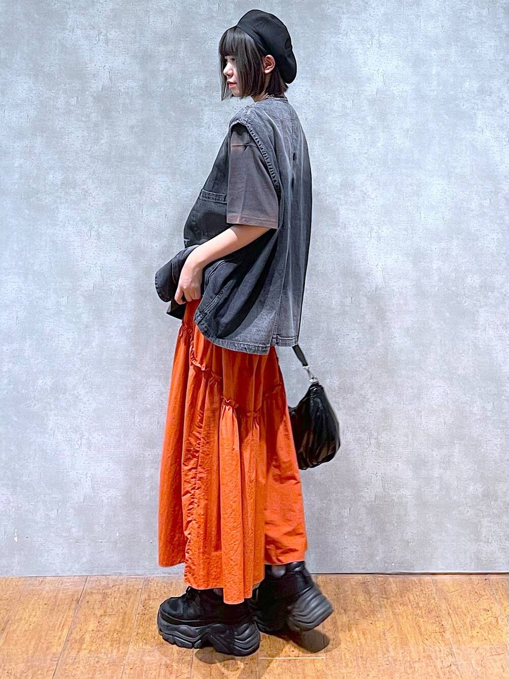 ブラック系のスニーカー、ブラック系のショルダーバッグ、オレンジ系のスカートを着用したレディースの夏コーディネートの4枚目の写真