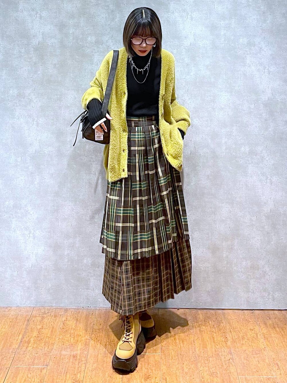 ブラック系のニット/セーター、ブラック系のショルダーバッグ、ブラウン系のブーツを着用したレディースの秋コーディネートの7枚目の写真