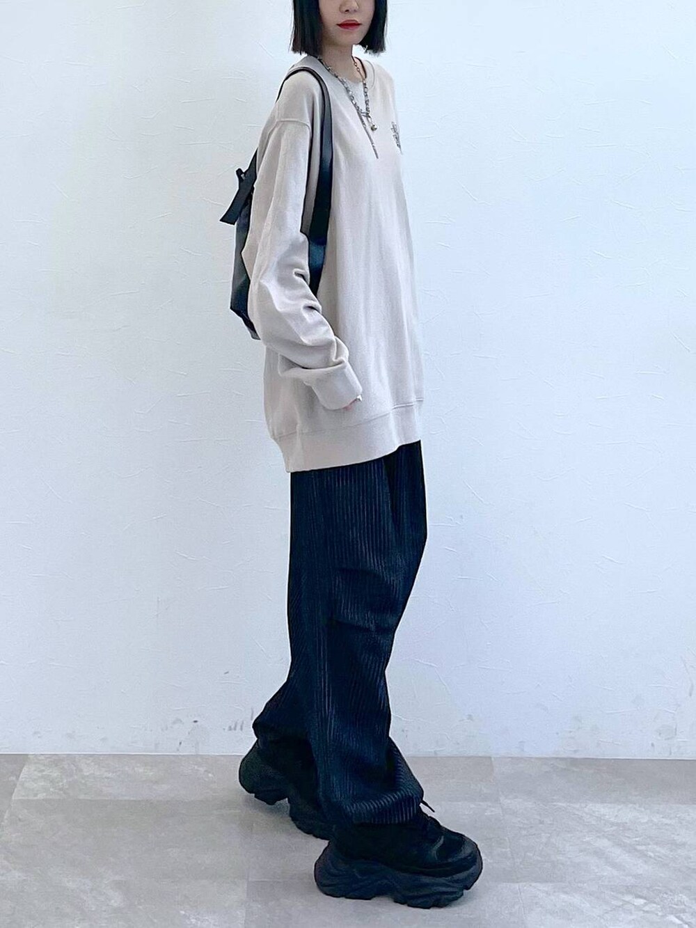 ブラック系のスニーカー、ブラック系のショルダーバッグ、ブラック系のデニムパンツを着用したレディースの秋コーディネートの4枚目の写真