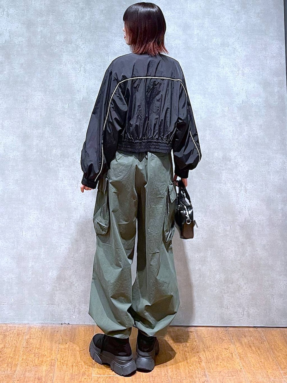 ブラック系のブルゾン、ホワイト系のTシャツ/カットソー、グリーン系のカーゴパンツを着用したレディースの春コーディネートの6枚目の写真