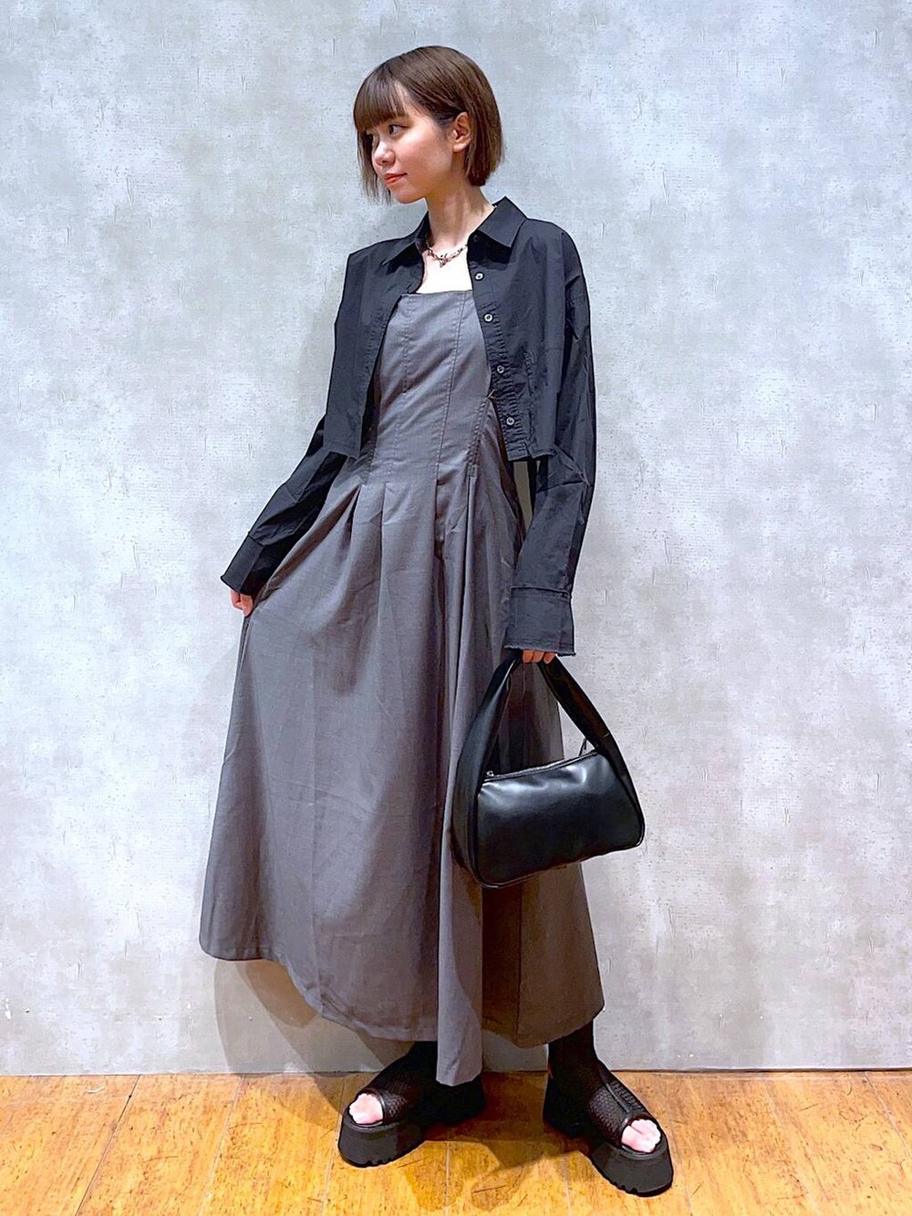 ブラック系のハンドバッグ、ブラック系のサンダル、ブラック系のシャツ/ブラウスを着用したレディースの夏コーディネートの2枚目の写真