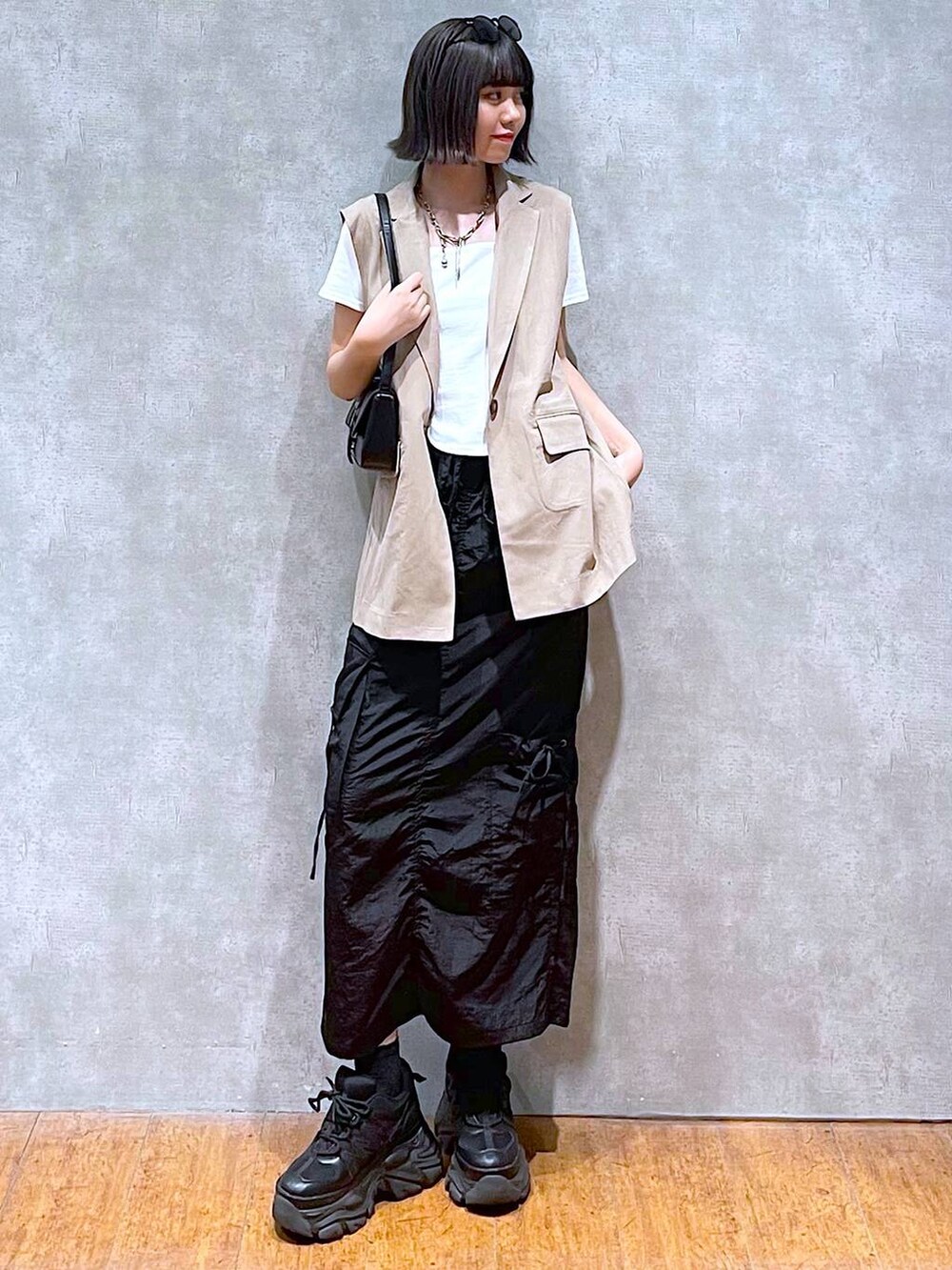 ブラック系のスニーカー、ブラック系のハンドバッグ、ホワイト系のTシャツ/カットソーを着用したレディースの夏コーディネートの5枚目の写真