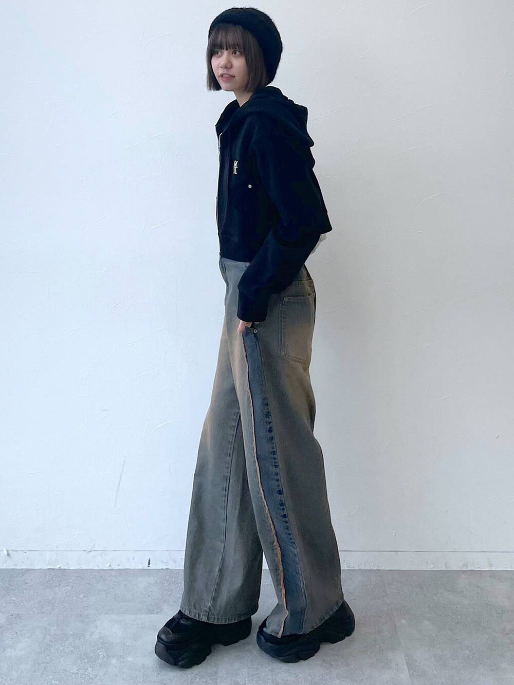 ブラック系のパーカー、ブラック系のスニーカー、ブルー系のデニムパンツを着用したレディースの秋コーディネートの5枚目の写真