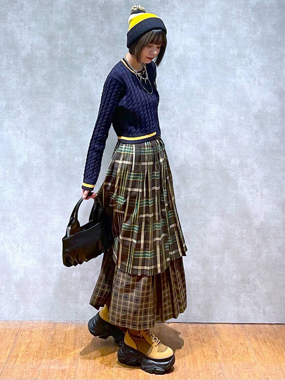 ブラウン系のブーツ、イエロー系のスカート、ブラック系のハンドバッグを着用したレディースの秋コーディネートの5枚目の写真
