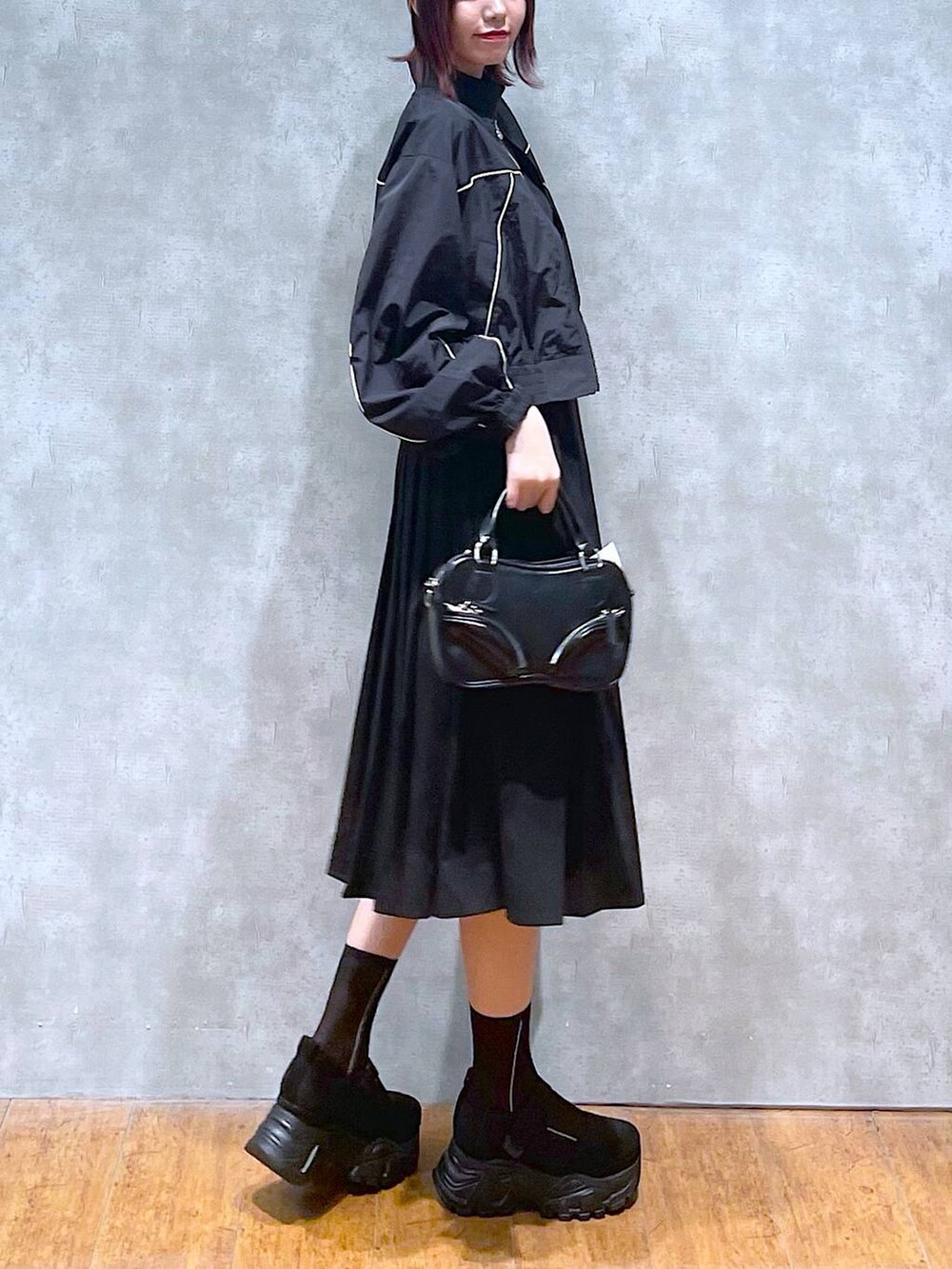 ブラック系のブルゾン、ブラック系のスカート、ブラック系のキャミソールを着用したレディースの春コーディネートの4枚目の写真