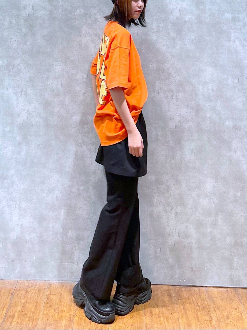 ブラック系のスニーカー、オレンジ系のTシャツ/カットソー、ブラック系のチノパンツを着用したレディースの夏コーディネートの6枚目の写真