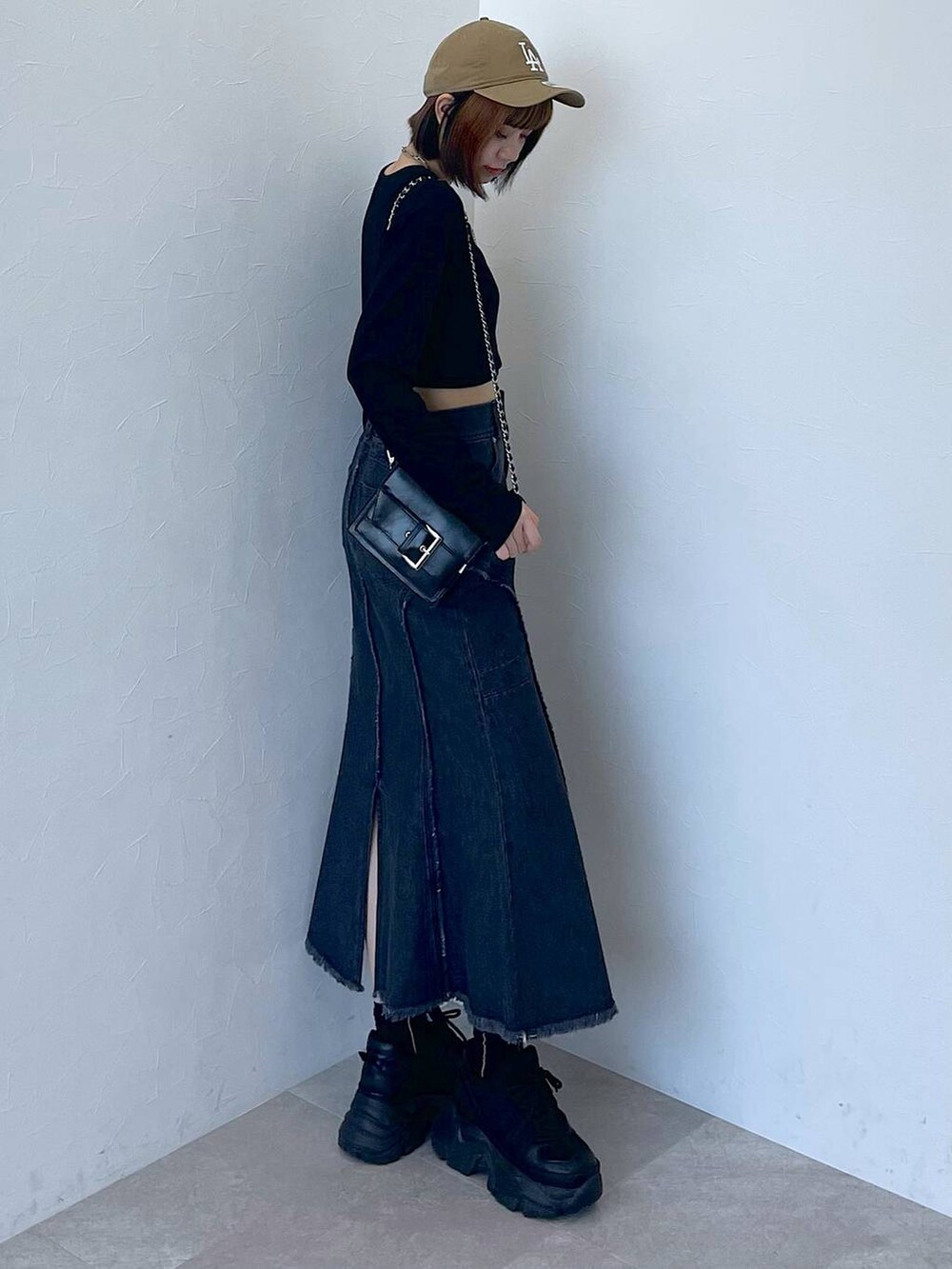 ブラック系のスニーカー、ブラック系のデニムスカート、ブラック系のTシャツ/カットソーを着用したレディースの秋コーディネートの3枚目の写真