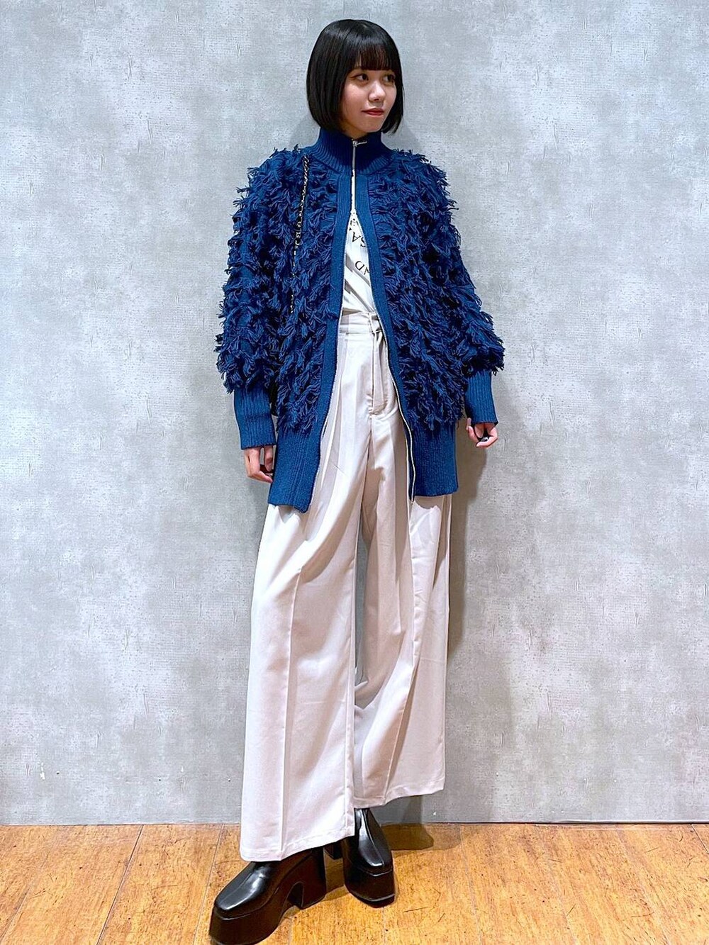 ブラック系のブーツ、ホワイト系のTシャツ/カットソー、ベージュ系のスラックスを着用したレディースの冬コーディネートの4枚目の写真