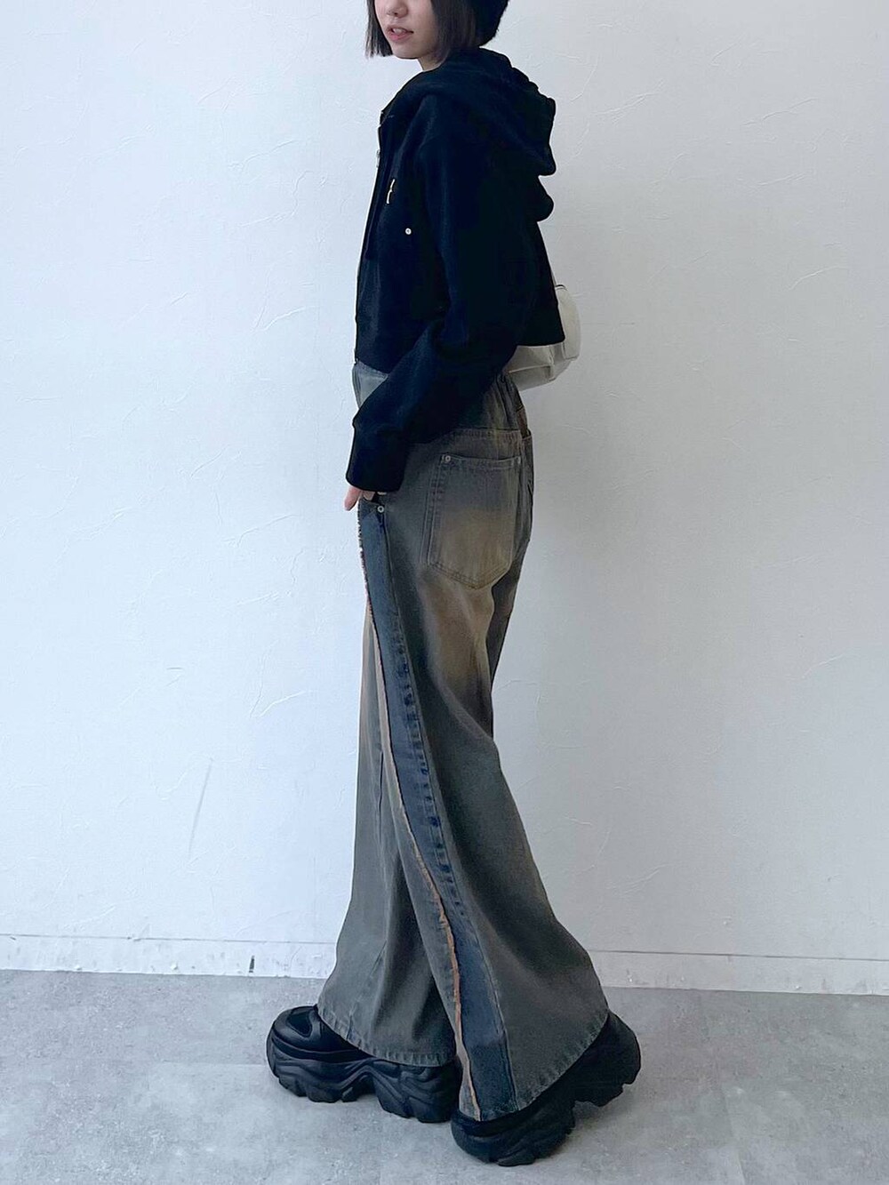 ブラック系のパーカー、ブラック系のスニーカー、ブルー系のデニムパンツを着用したレディースの秋コーディネートの7枚目の写真