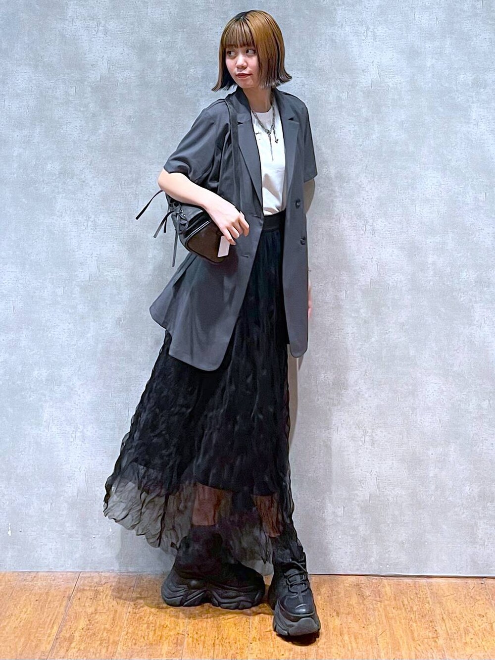 ブラック系のスニーカー、グレー系のテーラードジャケット、ホワイト系のTシャツ/カットソーを着用したレディースの夏コーディネートの3枚目の写真