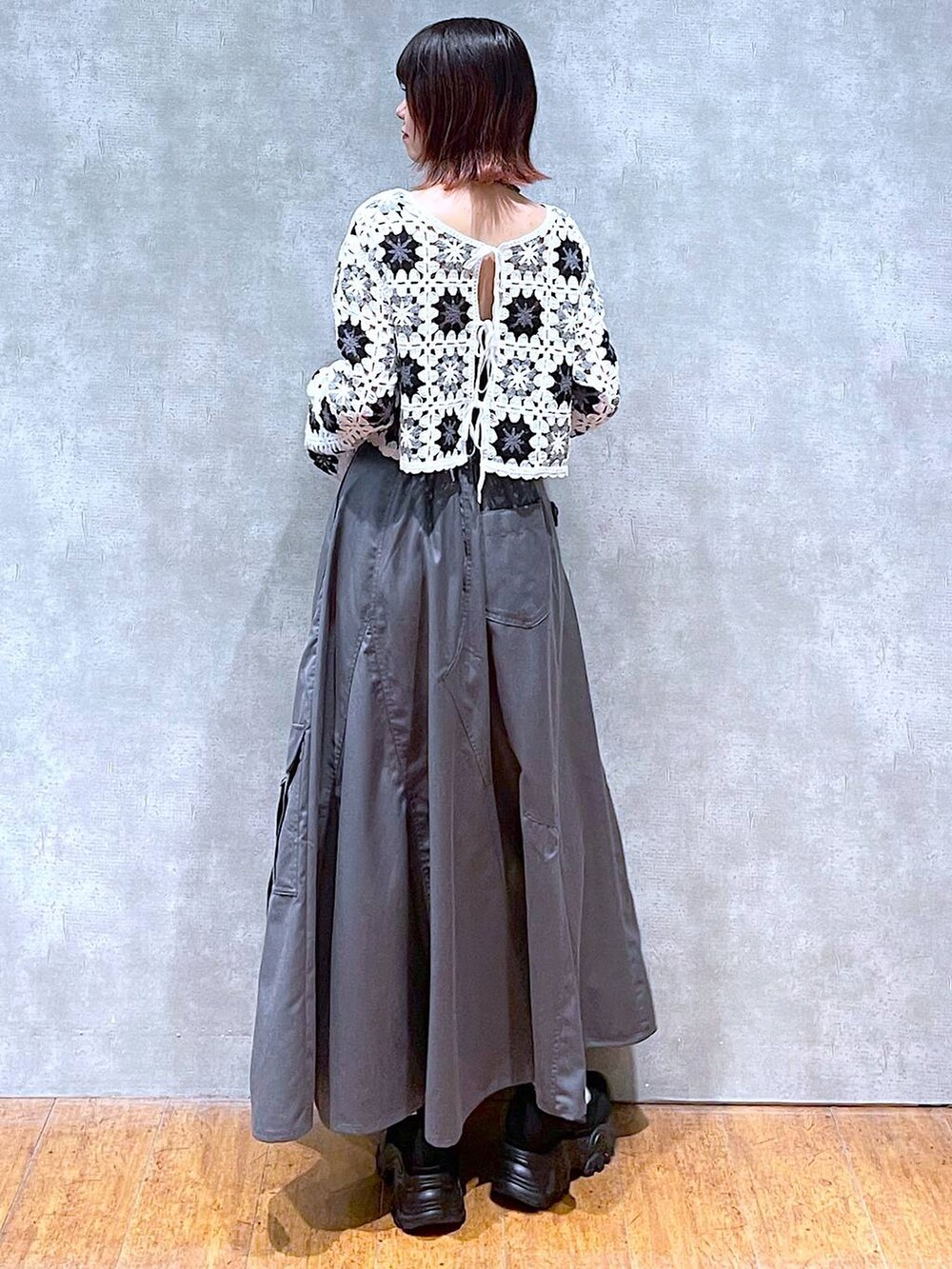 ホワイト系のカーディガン/ボレロ、ブラック系のキャミソール、グレー系のジャンパースカートを着用したレディースの春コーディネートの5枚目の写真