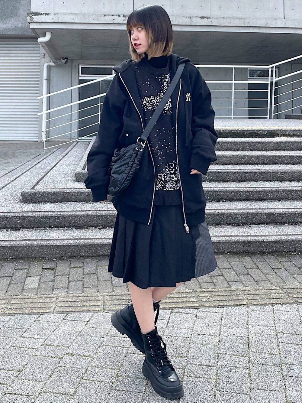 ブラック系のパーカー、ブラック系のショルダーバッグ、ブラック系のブーツを着用したレディースの冬コーディネートの4枚目の写真