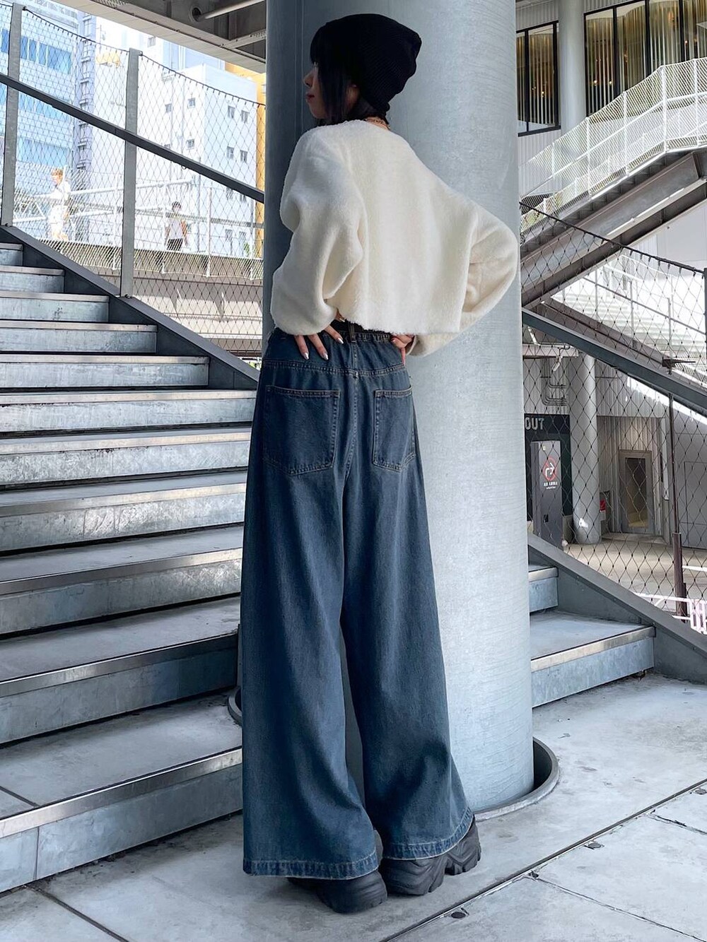 ブラック系のスニーカー、ブルー系のデニムパンツ、ホワイト系のニット/セーターを着用したレディースの秋コーディネートの6枚目の写真