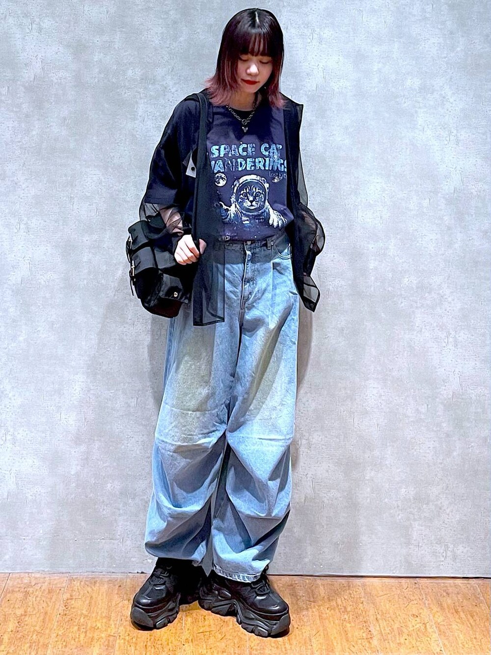 ブラック系のショルダーバッグ、ブルー系のデニムパンツ、ブラック系のスニーカーを着用したレディースの春コーディネートの3枚目の写真