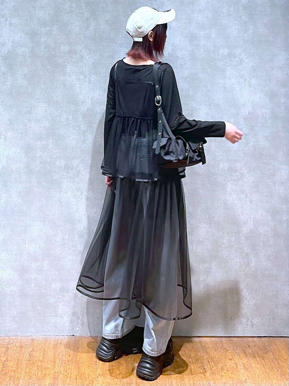 ブラック系のショルダーバッグ、ブラック系のスニーカー、ブルー系のデニムパンツを着用したレディースの春コーディネートの5枚目の写真