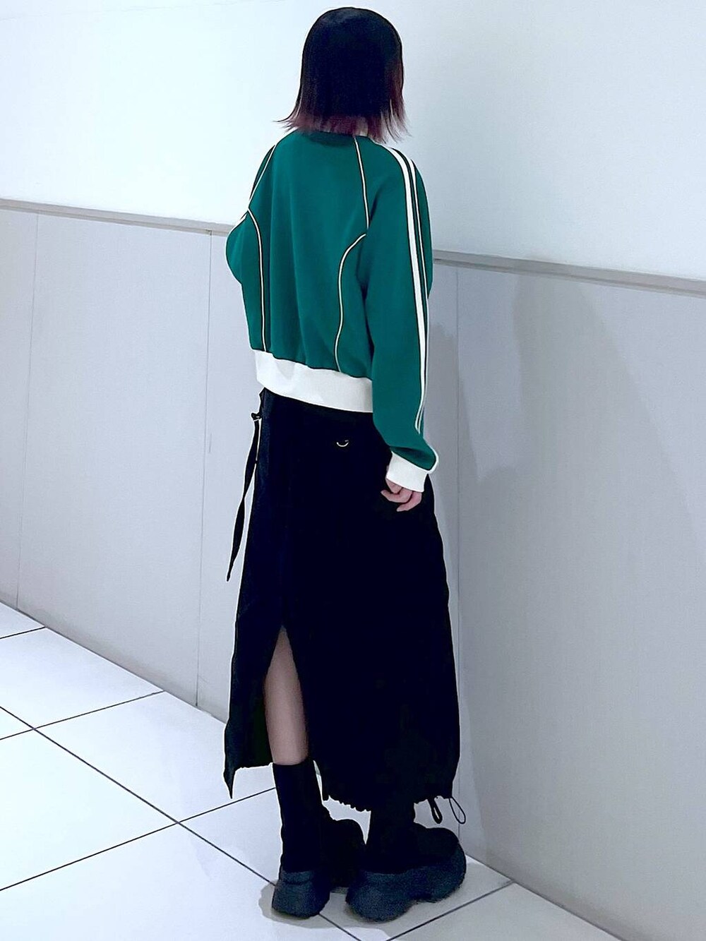 グリーン系のセットアップ、ブラック系のタンクトップ、ブラック系のブーツを着用したレディースの春コーディネートの5枚目の写真