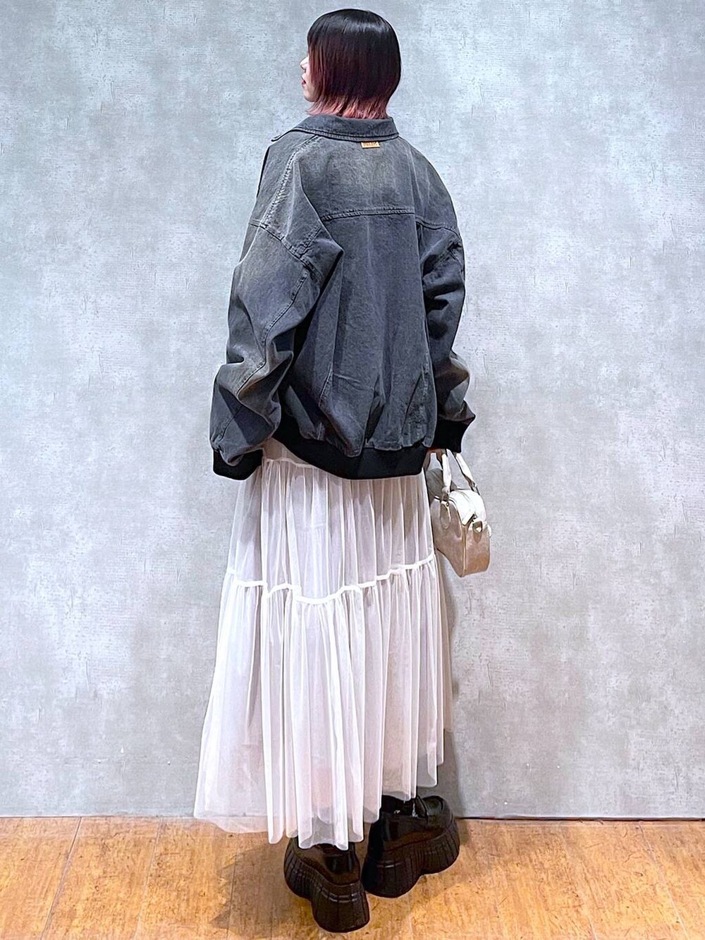 ブラック系のニット/セーター、ブラック系のデニムジャケット、ホワイト系のスカートを着用したレディースの冬コーディネートの8枚目の写真