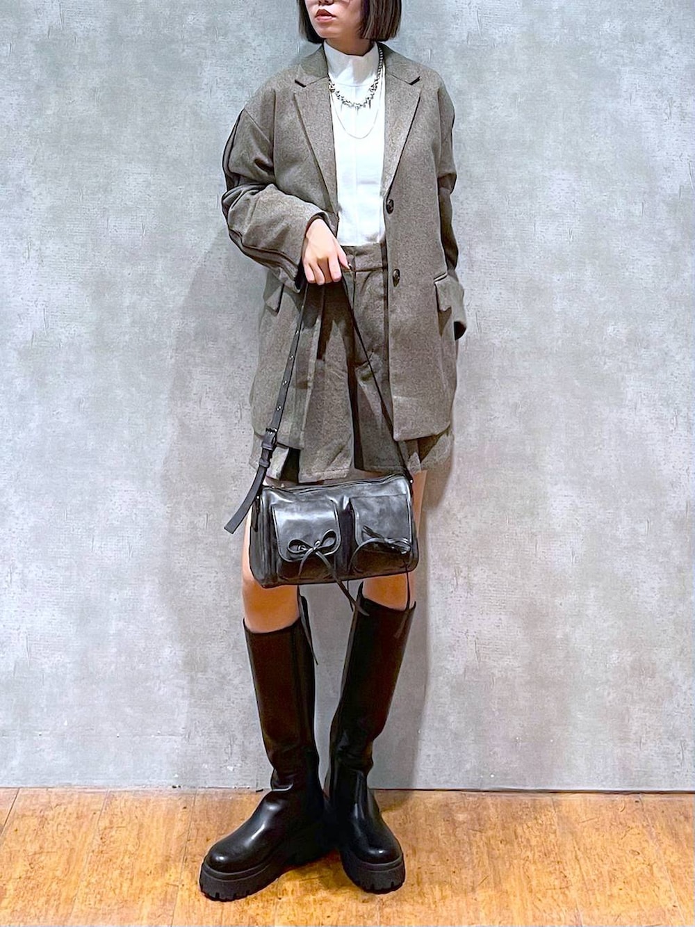 ブラック系のショルダーバッグ、ホワイト系のニット/セーター、ブラック系のブーツを着用したレディースの秋コーディネートの9枚目の写真