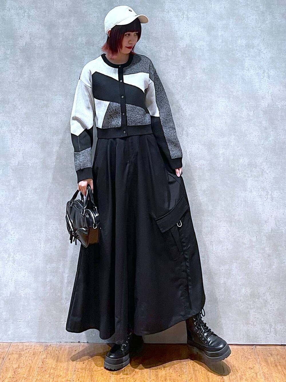 ブラック系のカーディガン/ボレロ、ブラック系のブーツ、ブラック系のジャンパースカートを着用したレディースの春コーディネートの3枚目の写真