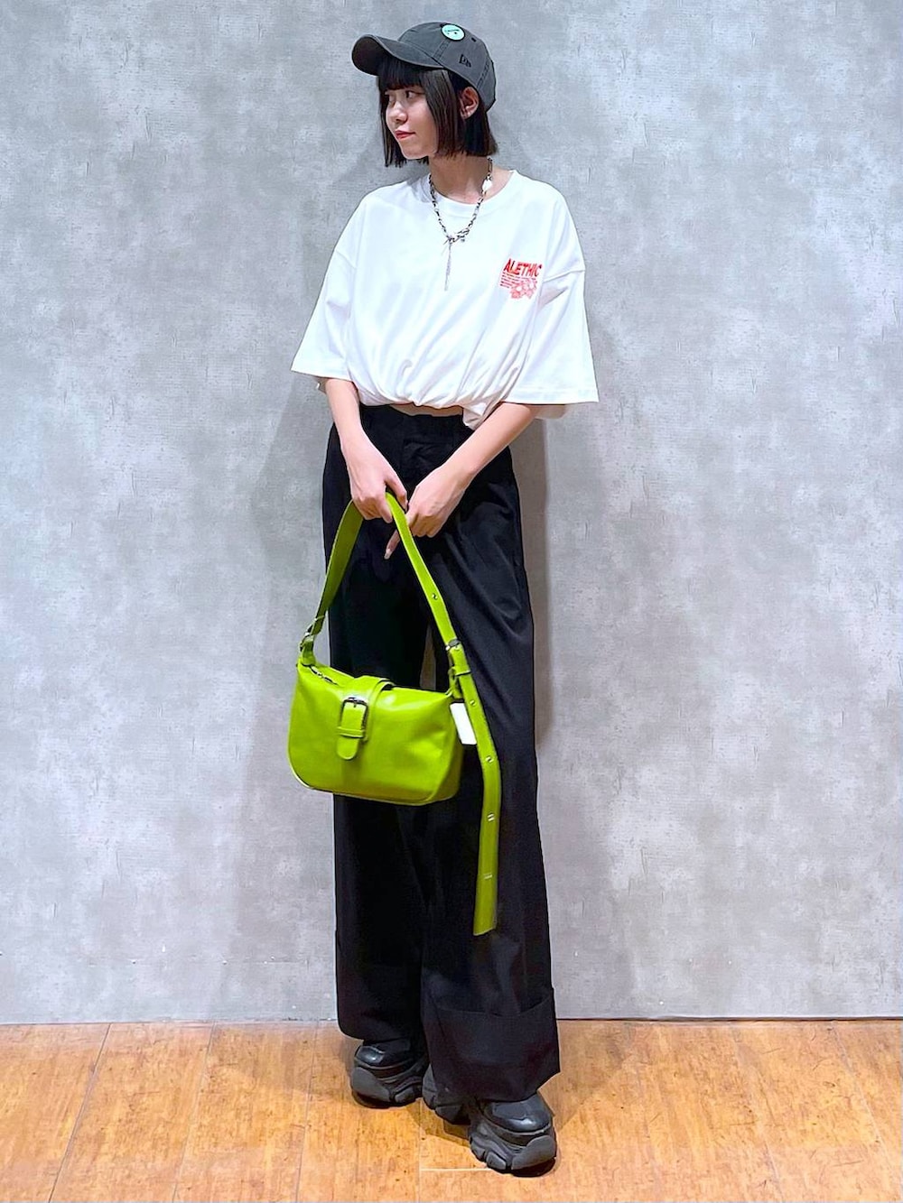 ブラック系のスニーカー、ホワイト系のTシャツ/カットソー、グリーン系のショルダーバッグを着用したレディースの夏コーディネートの2枚目の写真