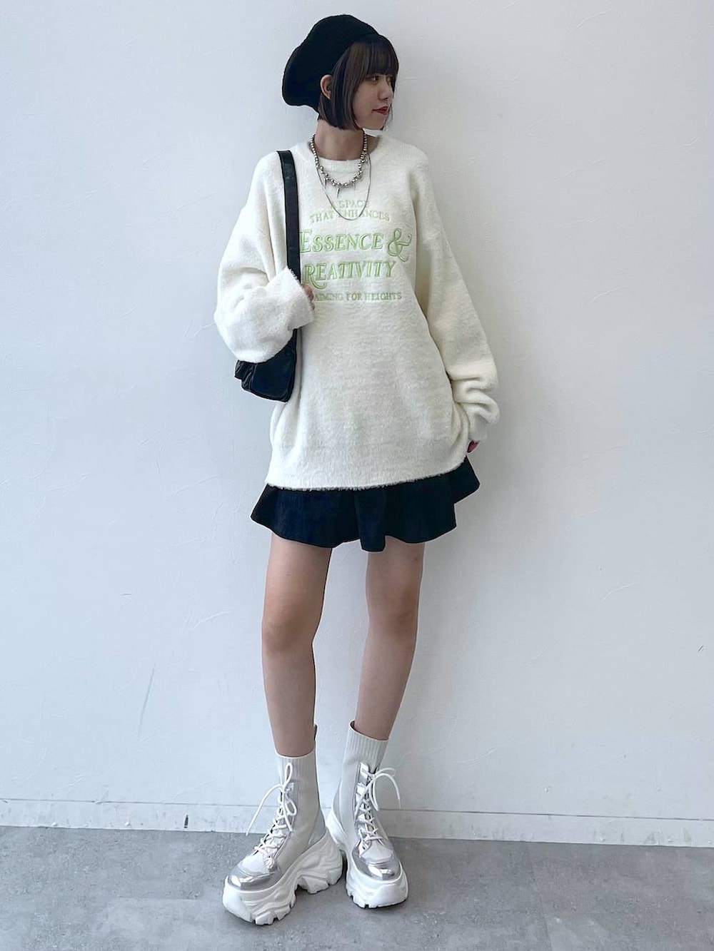 ホワイト系のブーツ、ブラック系のショルダーバッグ、ホワイト系のニット/セーターを着用したレディースの秋コーディネートの2枚目の写真