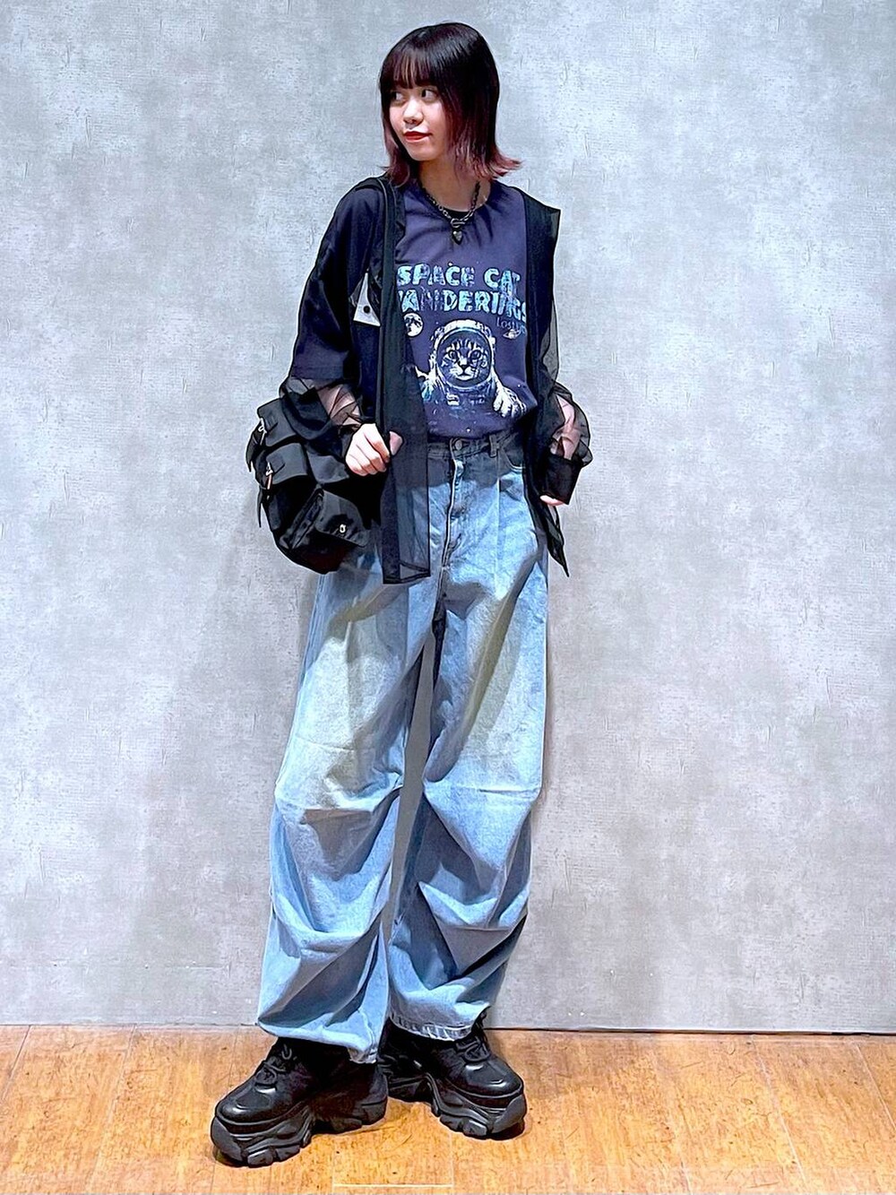 ブラック系のショルダーバッグ、ブルー系のデニムパンツ、ブラック系のスニーカーを着用したレディースの春コーディネートの4枚目の写真