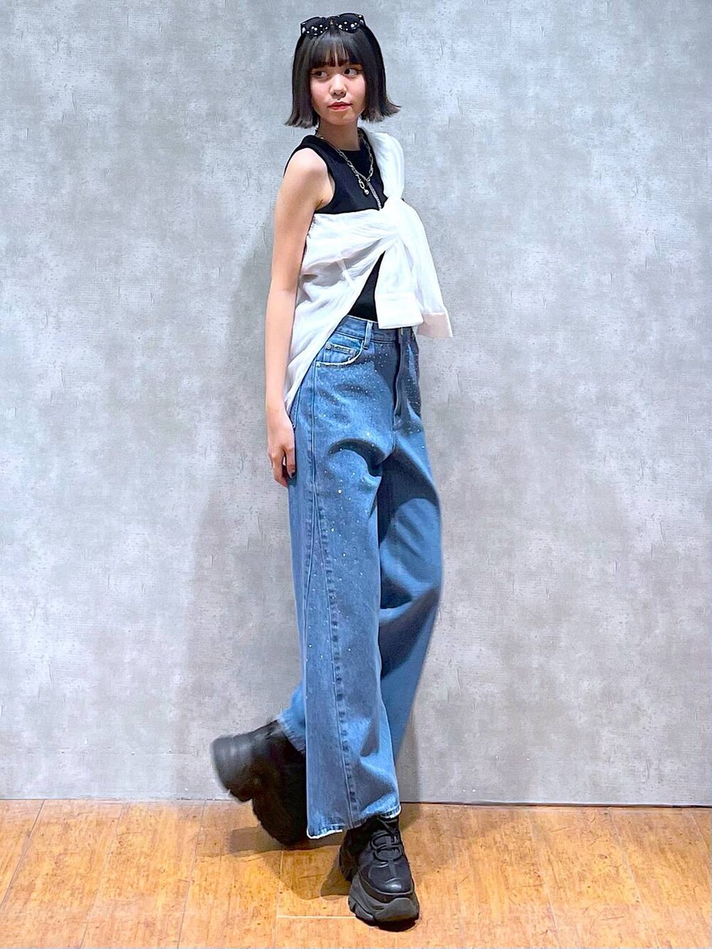 ブラック系のスニーカー、ブラック系のタンクトップ、ブルー系のデニムパンツを着用したレディースの夏コーディネートの4枚目の写真