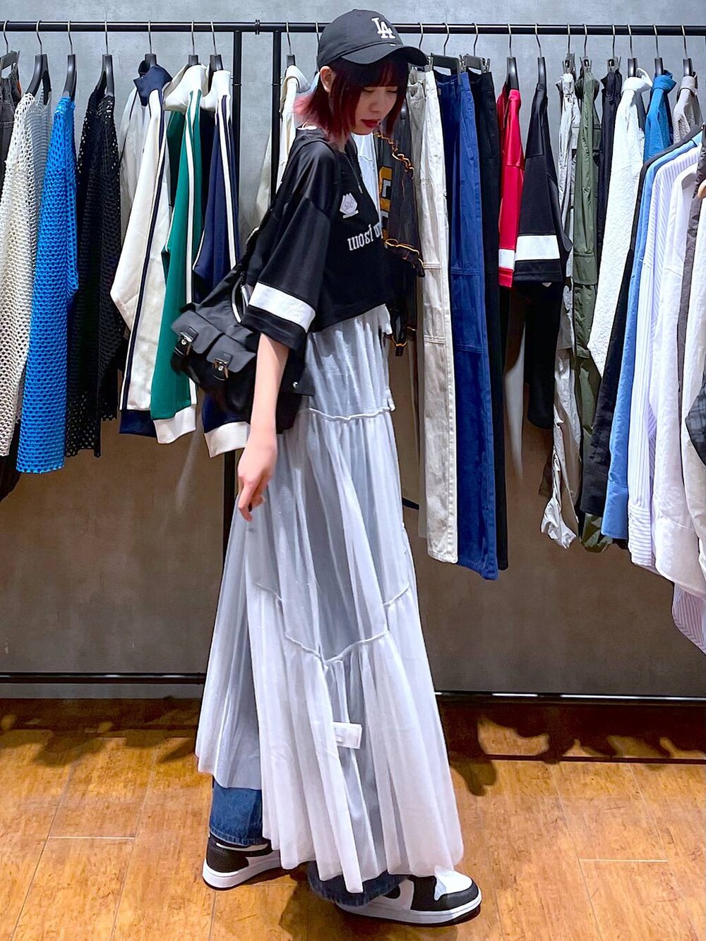 ブラック系のショルダーバッグ、ブルー系のデニムパンツ、ホワイト系のワンピースを着用したレディースの春コーディネートの5枚目の写真