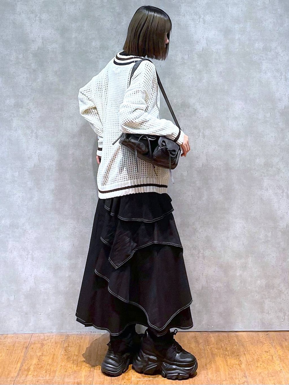 ブラック系のスニーカー、ブラック系のニット/セーター、ブラック系のショルダーバッグを着用したレディースの秋コーディネートの4枚目の写真