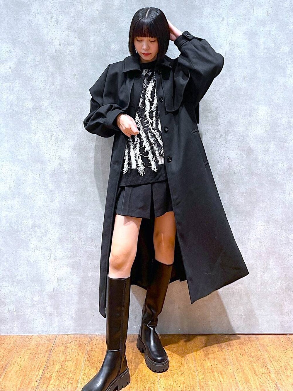 ブラック系のチェスターコート、ブラック系のブーツ、ブラック系のニット/セーターを着用したレディースの冬コーディネートの6枚目の写真