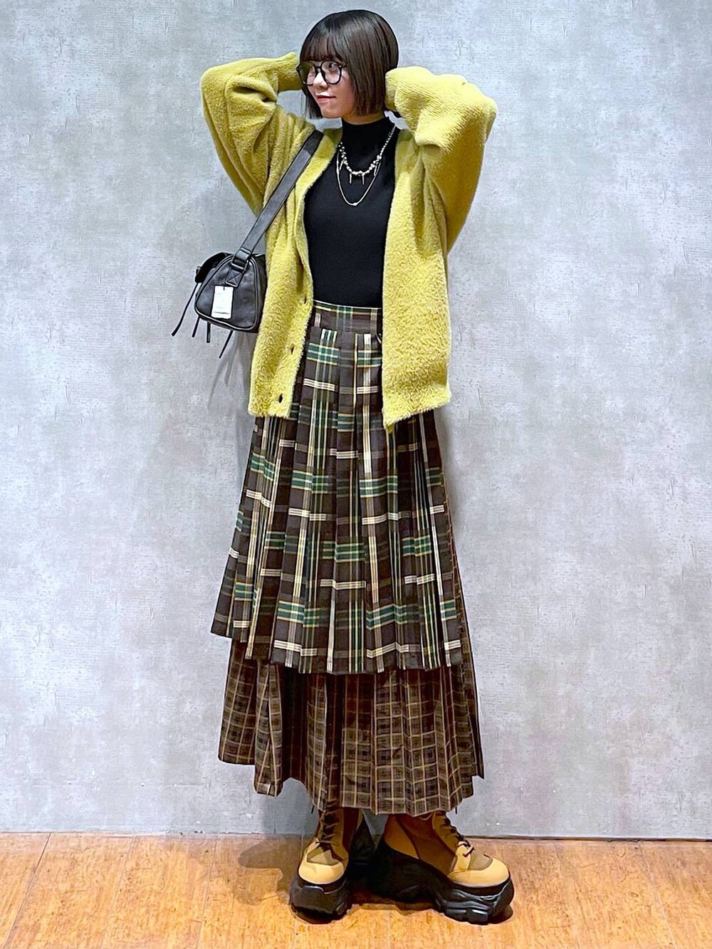 ブラック系のニット/セーター、ブラック系のショルダーバッグ、ブラウン系のブーツを着用したレディースの秋コーディネートの2枚目の写真