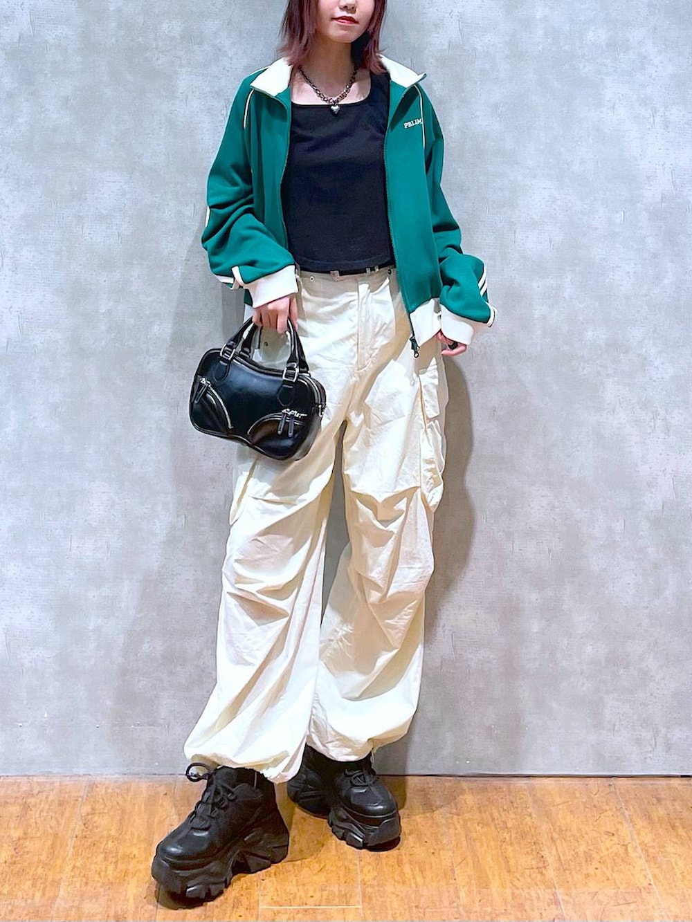 グリーン系のセットアップ、ブラック系のボストンバッグ、ホワイト系のカーゴパンツを着用したレディースの春コーディネートの3枚目の写真