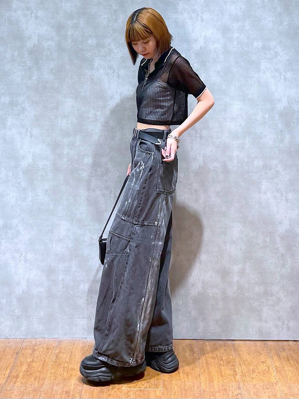 ブラック系のスニーカー、ホワイト系のキャミソール、ブラック系のデニムパンツを着用したレディースの夏コーディネートの5枚目の写真