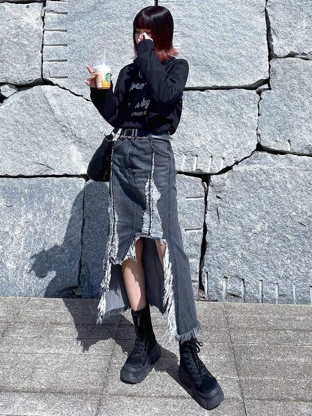 ブラック系のショルダーバッグ、ブラック系のブーツ、ブラック系のデニムスカートを着用したレディースの春コーディネートの3枚目の写真