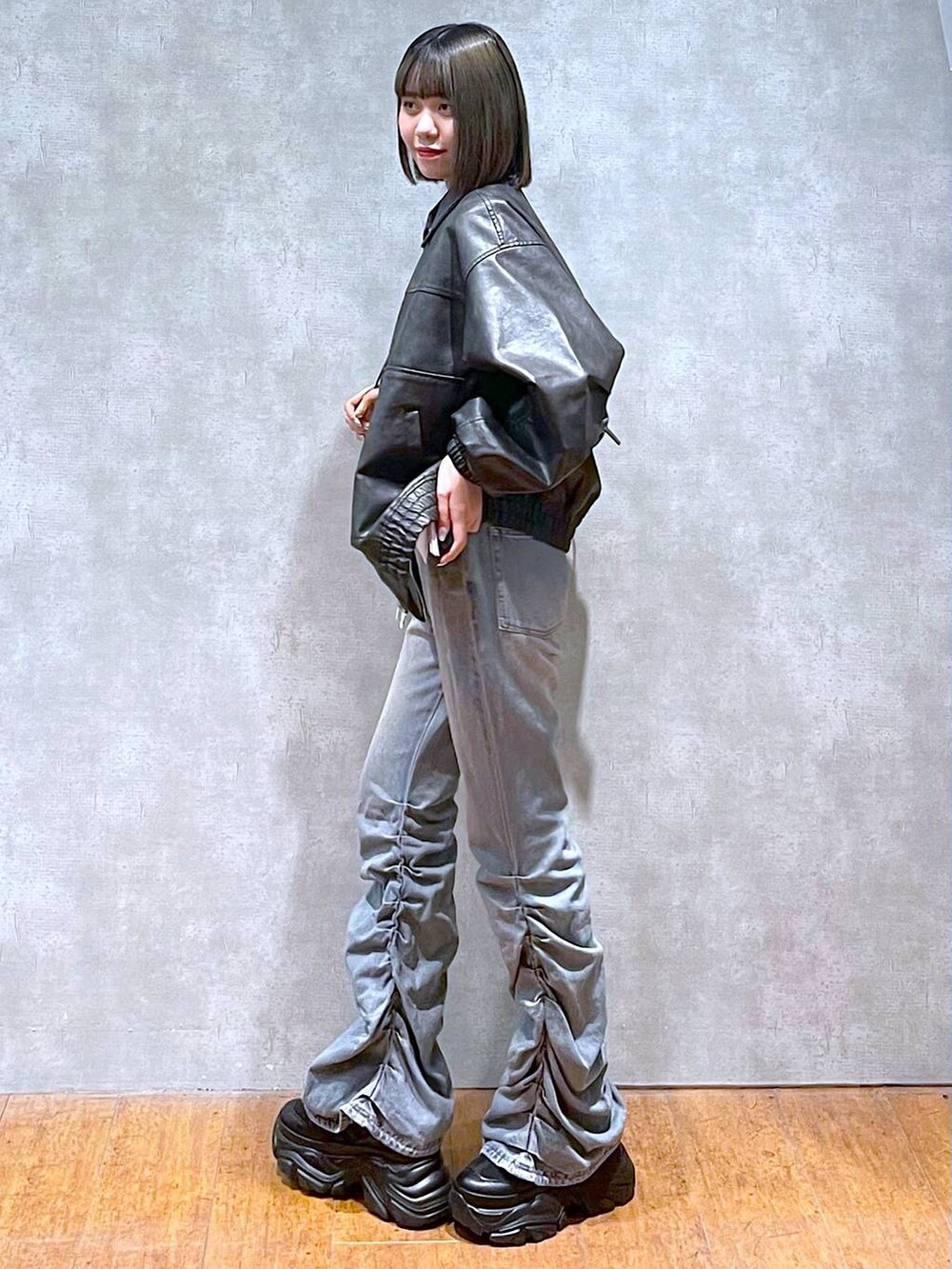 ブラック系のスニーカー、ブラック系のショルダーバッグ、ブルー系のデニムパンツを着用したレディースの秋コーディネートの5枚目の写真