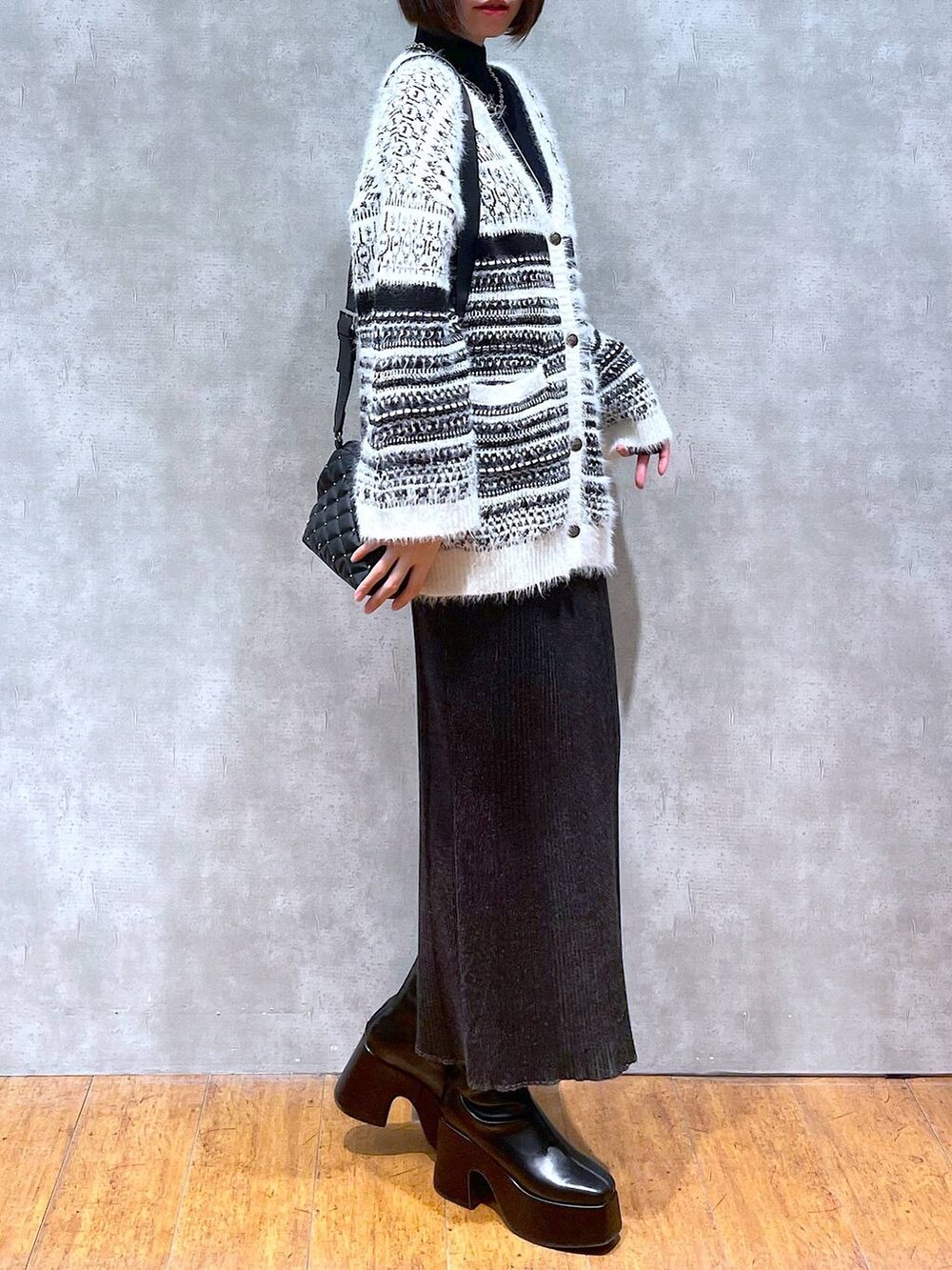 ブラック系のニット/セーター、ブラック系のブーツ、ブラック系のショルダーバッグを着用したレディースの冬コーディネートの3枚目の写真