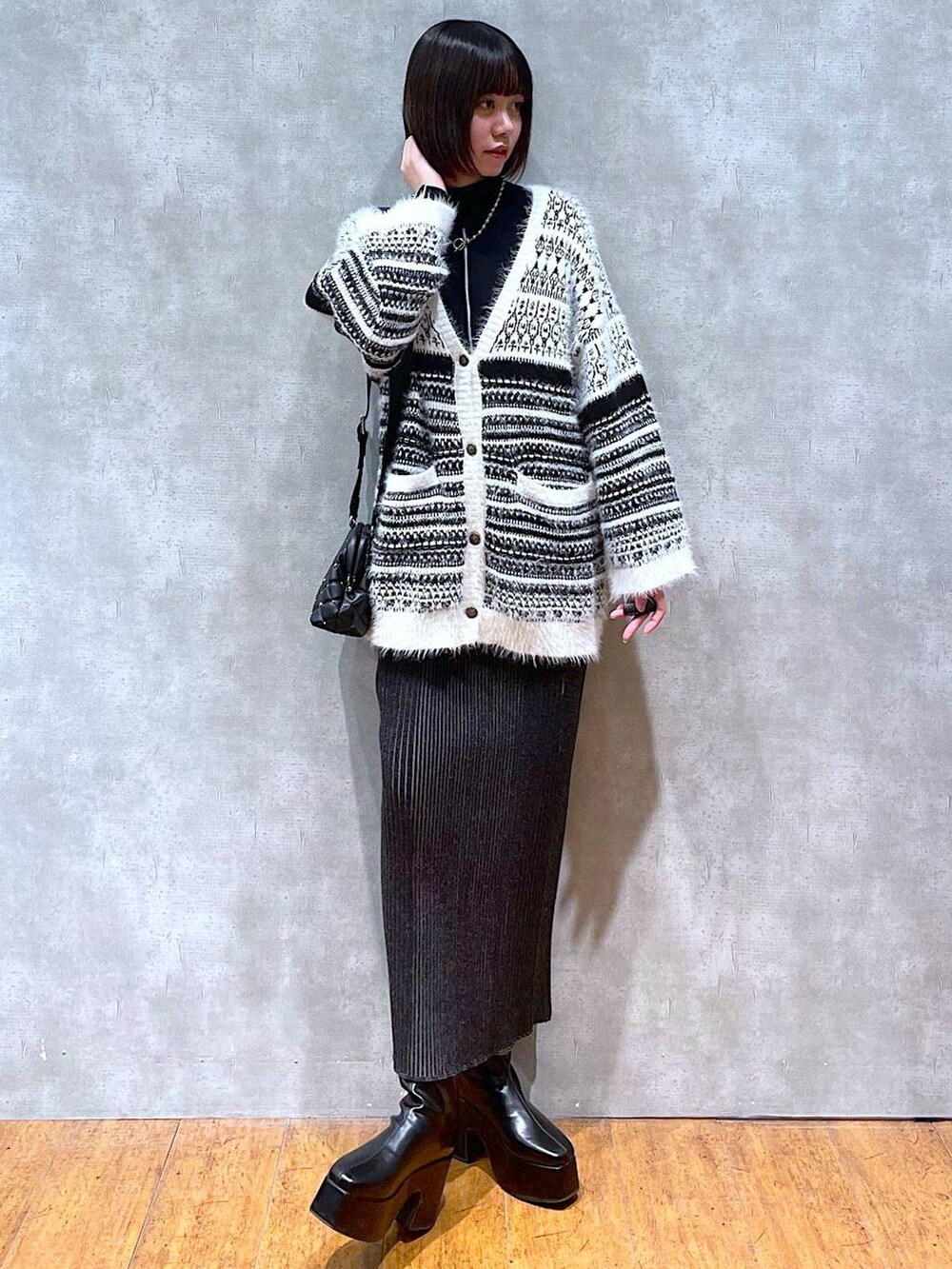 ブラック系のニット/セーター、ブラック系のブーツ、ブラック系のショルダーバッグを着用したレディースの冬コーディネートの4枚目の写真