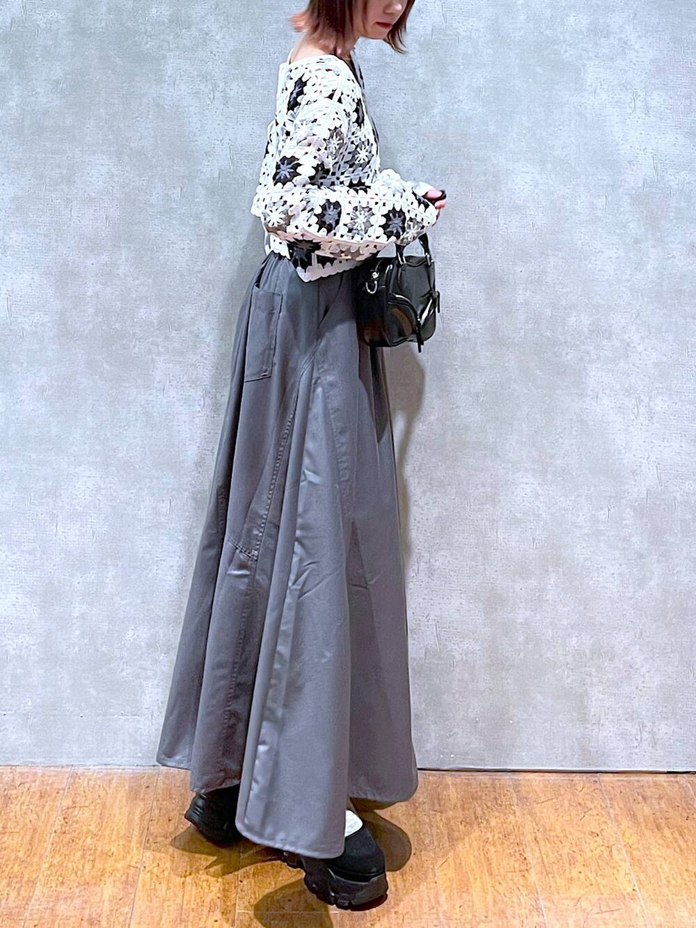 ホワイト系のカーディガン/ボレロ、ブラック系のキャミソール、グレー系のジャンパースカートを着用したレディースの春コーディネートの4枚目の写真