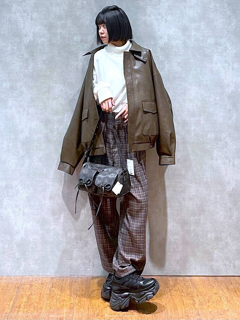 ブラック系のスニーカー、ブラック系のショルダーバッグ、ブラウン系のブルゾンを着用したレディースの秋コーディネートの2枚目の写真