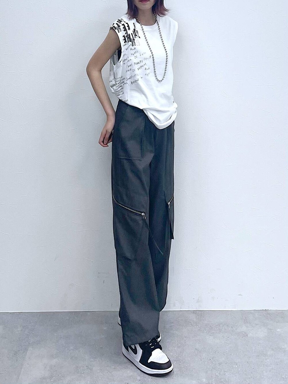 グレー系のスラックス、ホワイト系のTシャツ/カットソー、シルバー系のネックレスを着用したレディースの夏コーディネートの4枚目の写真