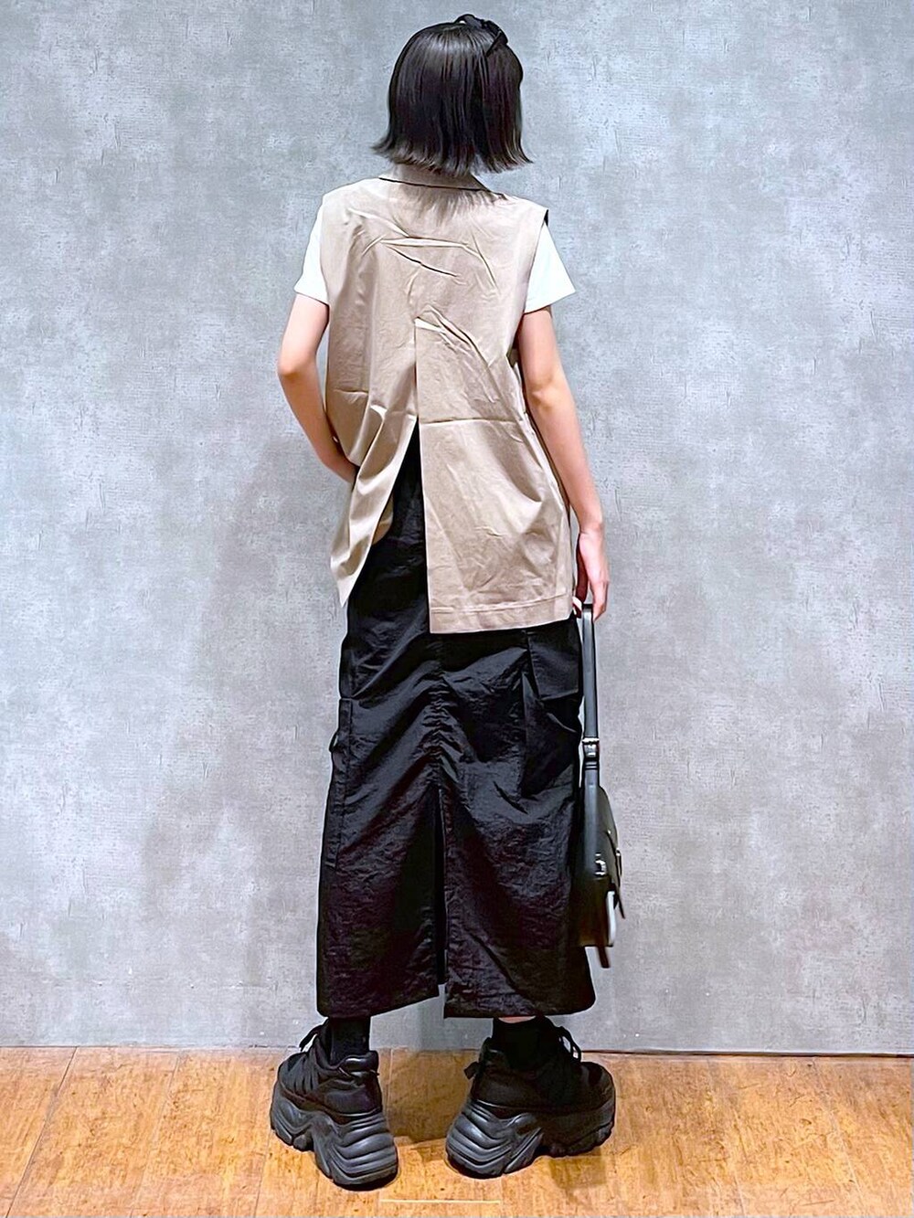 ブラック系のスニーカー、ブラック系のハンドバッグ、ホワイト系のTシャツ/カットソーを着用したレディースの夏コーディネートの6枚目の写真