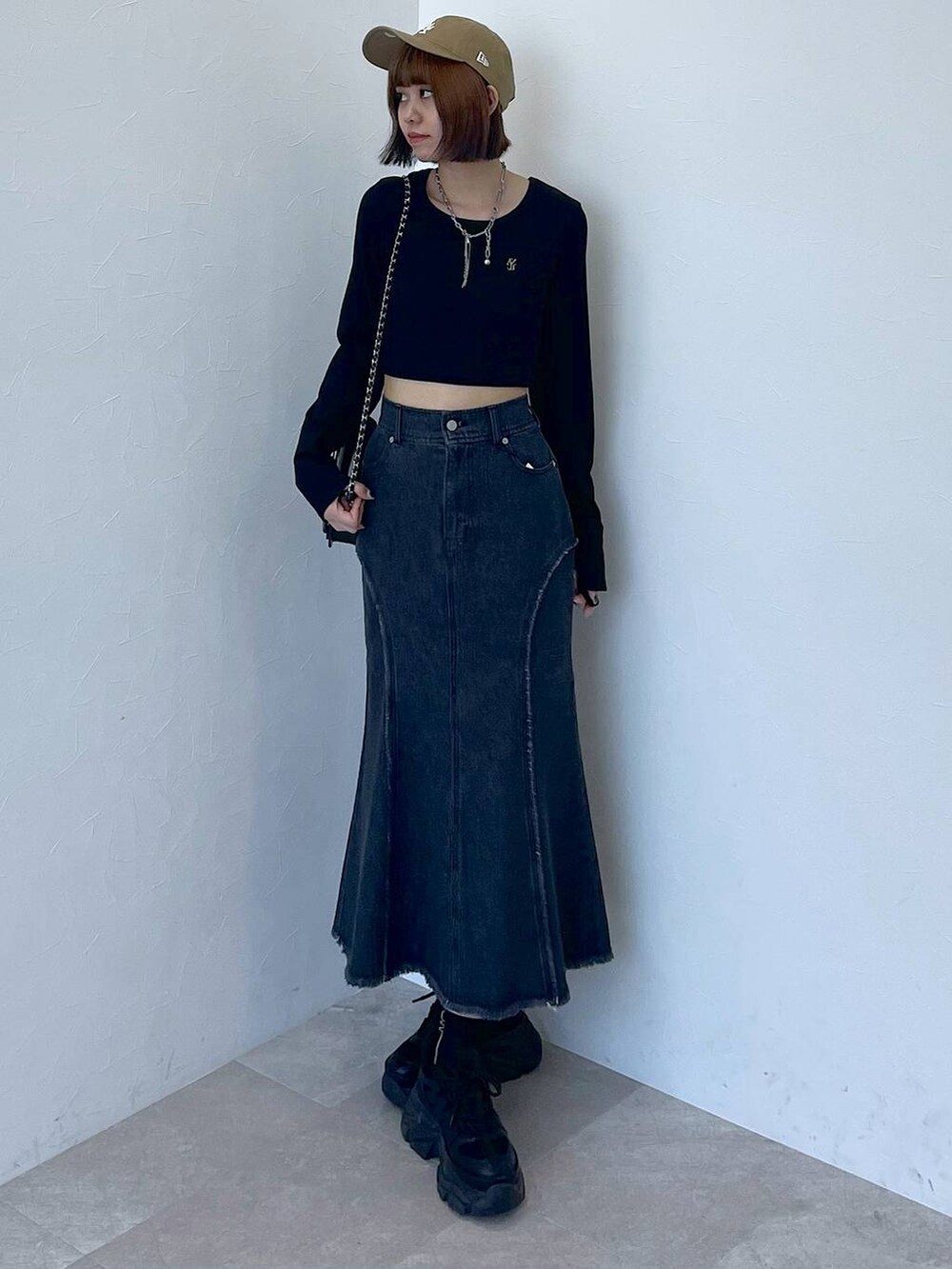 ブラック系のスニーカー、ブラック系のデニムスカート、ブラック系のTシャツ/カットソーを着用したレディースの秋コーディネートの7枚目の写真