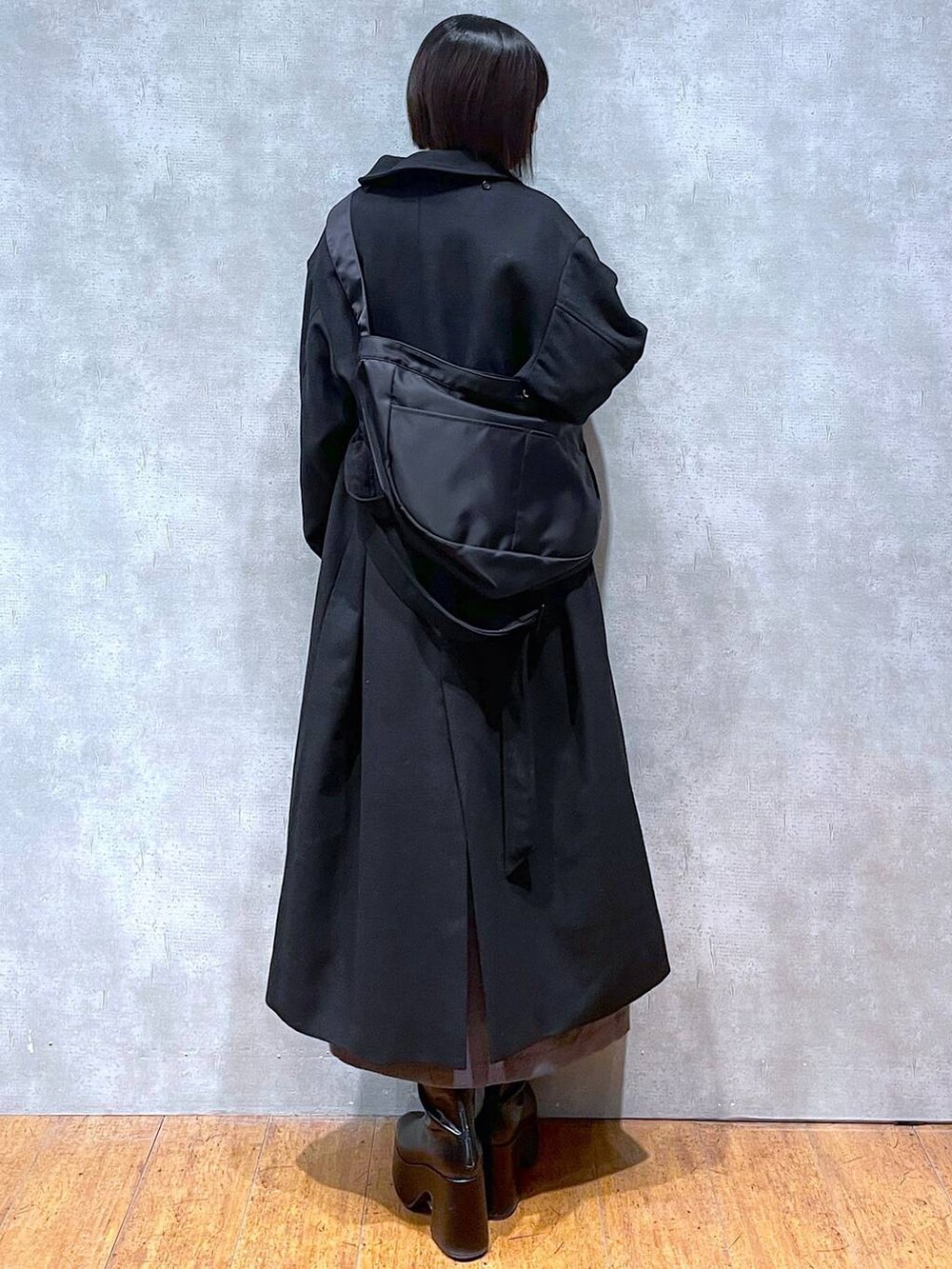 グレー系のスカート、ブラック系のチェスターコート、ブラック系のブーツを着用したレディースの冬コーディネートの4枚目の写真