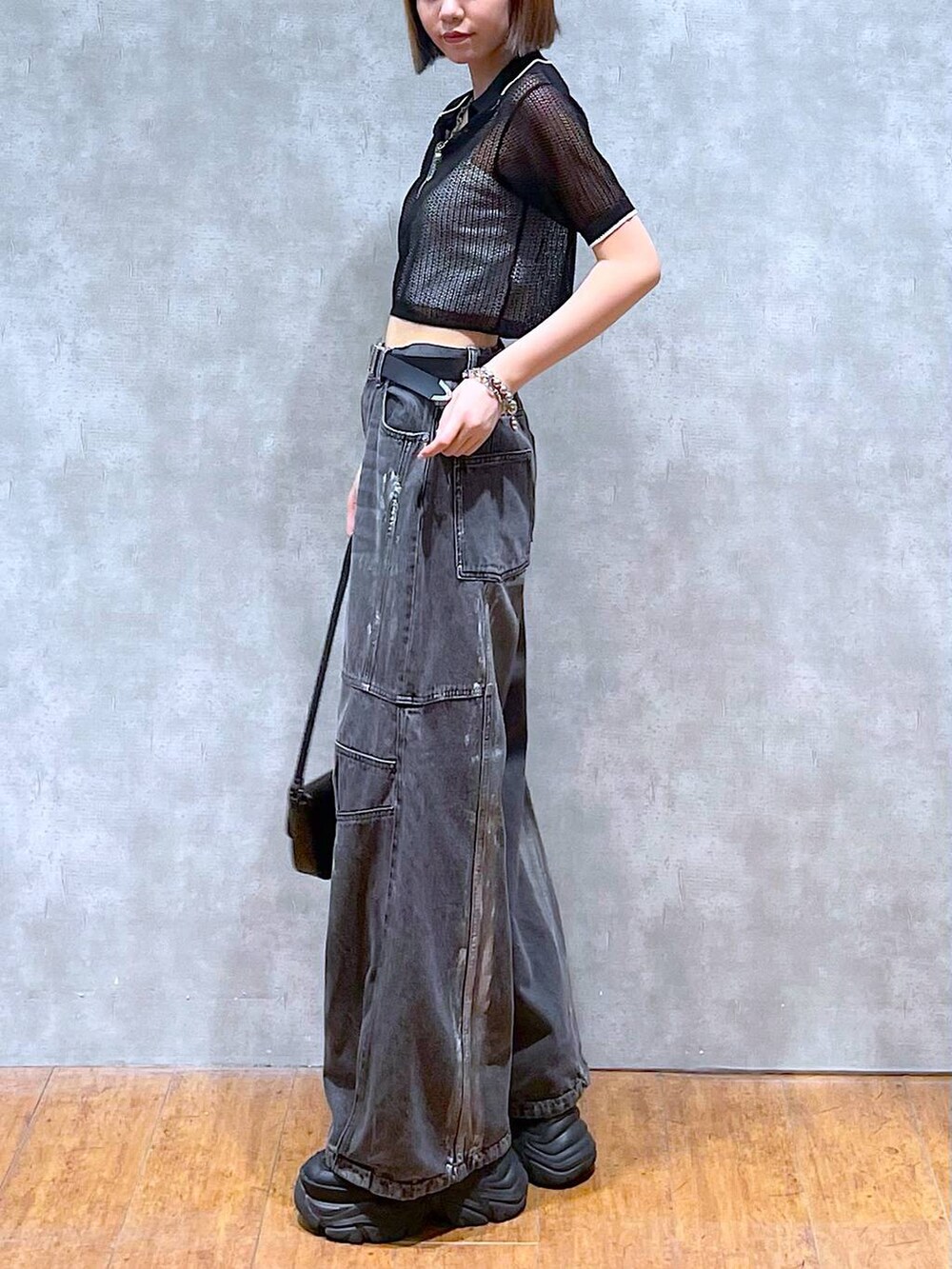 ブラック系のスニーカー、ホワイト系のキャミソール、ブラック系のデニムパンツを着用したレディースの夏コーディネートの6枚目の写真