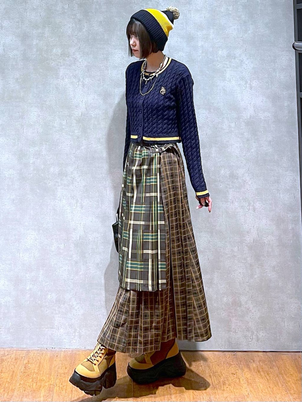 ブラウン系のブーツ、イエロー系のスカート、ブラック系のハンドバッグを着用したレディースの秋コーディネートの6枚目の写真