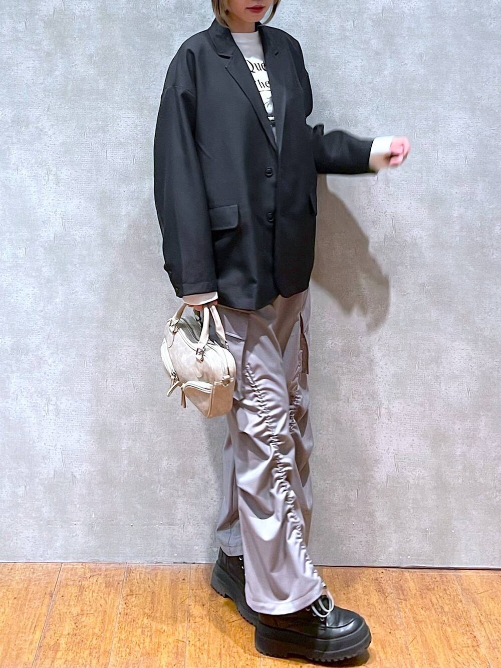 ブラック系のテーラードジャケット、ホワイト系のTシャツ/カットソー、ブラック系のブーツを着用したレディースの冬コーディネートの3枚目の写真