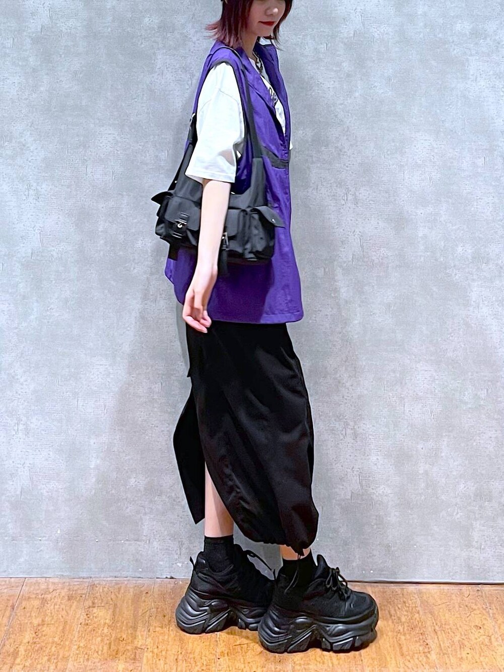 ブラック系のショルダーバッグ、ブラック系のスニーカー、パープル系のベストを着用したレディースの春コーディネートの4枚目の写真