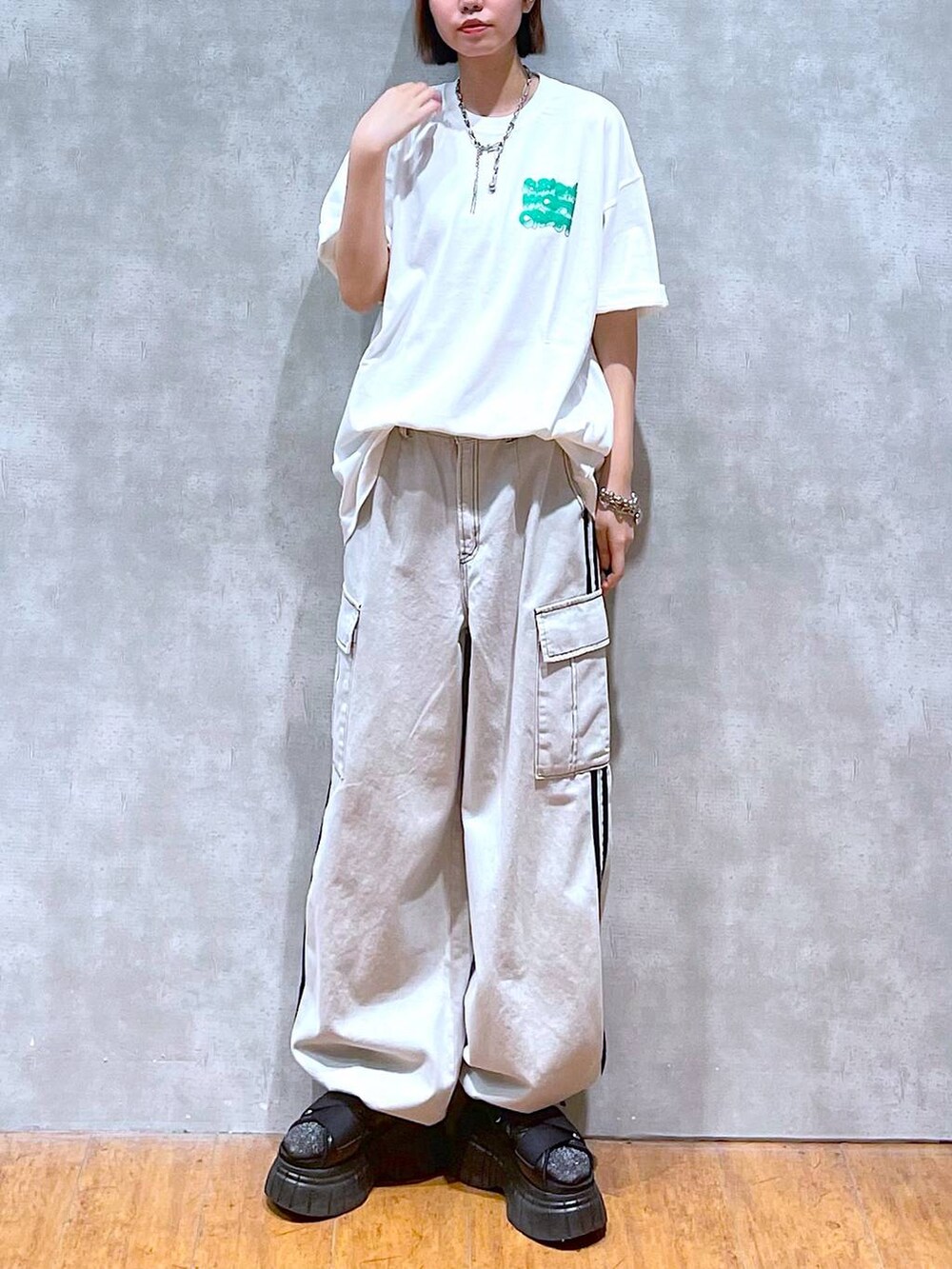 ブラック系のスニーカー、ホワイト系のTシャツ/カットソー、ホワイト系のデニムパンツを着用したレディースの夏コーディネートの5枚目の写真